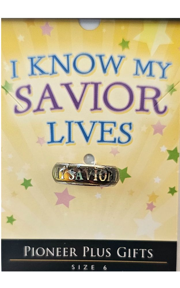 A silver-colored mood ring with the inscription 'I KNOW MY SAVIOR LIVES' displayed on a packaging with star decorations around it.